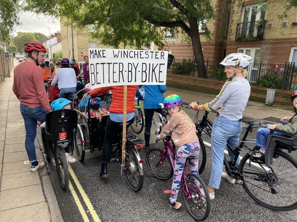 Family cyclists with banner: Make Winchester Better by Bike