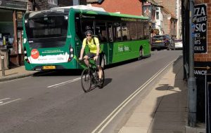 A cyclist crossing City Bridge in an easterly direction, surrounded by a bus and busy traffic